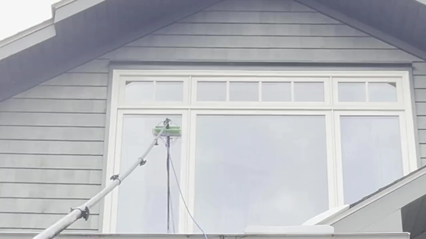 Purified Wash cleaning a large upstairs window from the driveway with a water fed pole