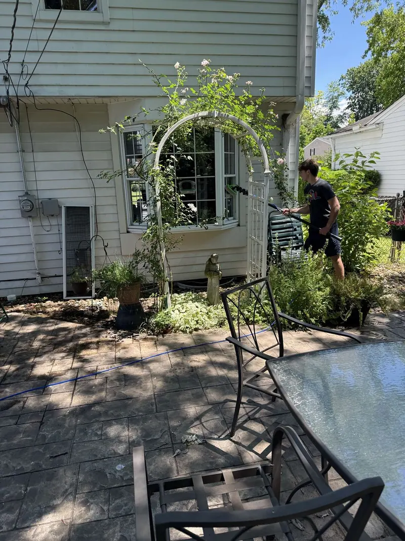 Washing a stamped patio beside a rose arbor